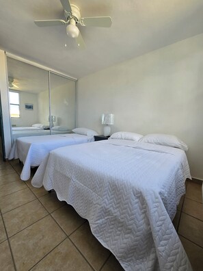 A hotel room with two beds, a ceiling fan, a large mirror, and a lamp. - Beach-5 Pools-25 Min from airport-Unit with reserve water system  (Loíza)