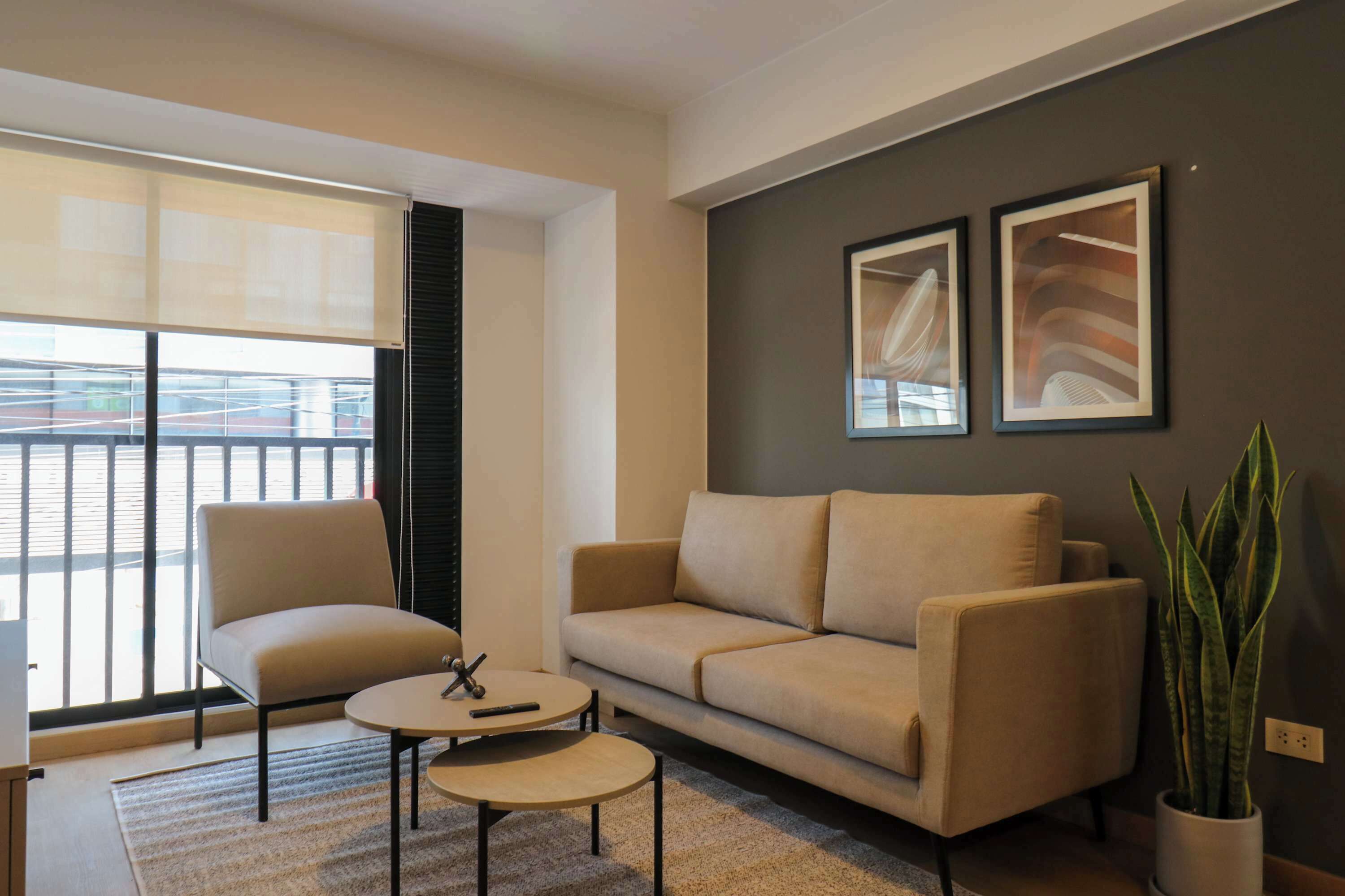 A modern living room with a sofa, armchair, coffee table, and a potted plant.