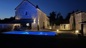 A stone building with a swimming pool in front, surrounded by well-lit areas and a gated entrance. - Rives de Seine - NEUVILLE SUR SEINE (NEUVILLE SUR SEINE)