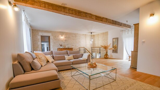 A modern living room with a sectional sofa, a glass coffee table, and a stone wall. - Rives de Seine - NEUVILLE SUR SEINE (NEUVILLE SUR SEINE)