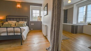 A bedroom with a bed, a radiator, a window, and a bathroom with a bathtub. - Rives de Seine - NEUVILLE SUR SEINE (NEUVILLE SUR SEINE)
