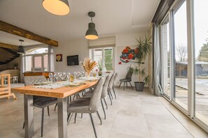 A modern dining area with a long wooden table, grey upholstered chairs, and pendant lighting. - Rives de Seine - NEUVILLE SUR SEINE (NEUVILLE SUR SEINE)