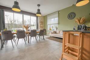 A modern dining area with a wooden table and chairs, a sofa, and a coffee machine. - Rives de Seine - NEUVILLE SUR SEINE (NEUVILLE SUR SEINE)