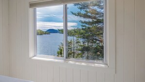 A window with a view of a lake and trees. - Pondside Cottage w/ Dock & Patio! [Loons Nest] (Mount Desert)
