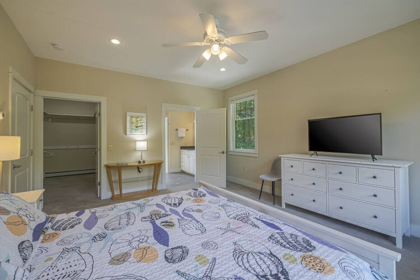 A bedroom with a bed, a dresser, a television, a desk, and a closet.