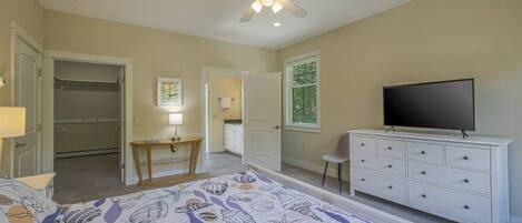 A bedroom with a bed, a dresser, a television, a desk, and a closet.