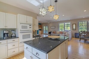 Une cuisine spacieuse avec des meubles blancs, un plan de travail en granit et un îlot central.