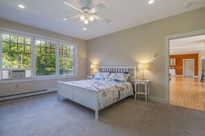 A bedroom with a bed, a ceiling fan, a nightstand, and a window with a view of trees. - Spacious 5BR Home in Center of MDI [Loons Landing] (Mount Desert)