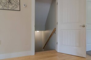 A hallway with a wooden handrail, a white door, and a framed picture on the wall.