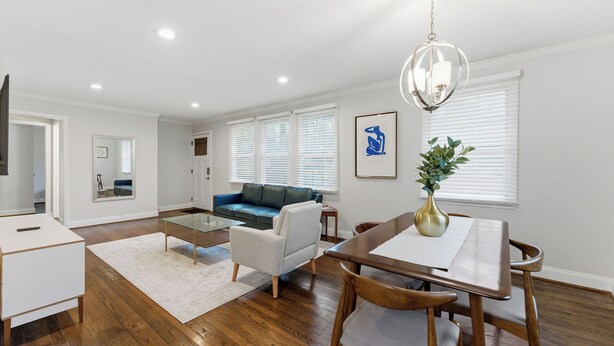 A modern living room with a dining area, wooden flooring, a blue sofa, and a chandelier. - Comfortable & Quiet 3BR Home Near Downtown ATL (Atlanta)