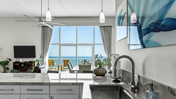 Een moderne keuken met een ruim kookeiland, een eetgedeelte met uitzicht, en een balkon met uitzicht op de oceaan.