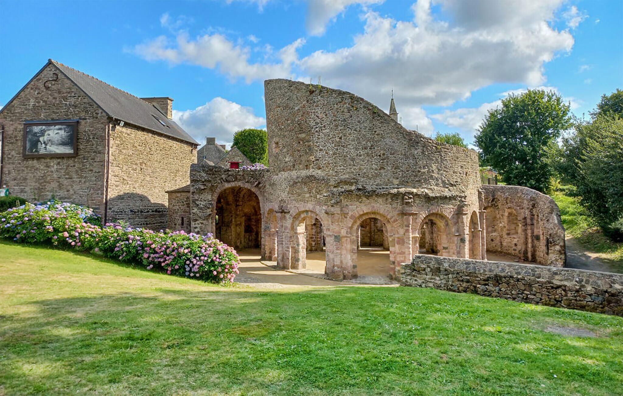 Un bâtiment historique en pierre, doté d’une entrée en arc de cercle et d’un grand mur de pierre.