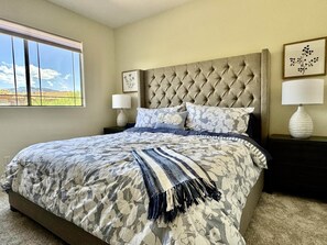 A bedroom with a large bed, a tufted headboard, a window with a view, and two bedside tables with lamps. - Vistoso Condo #212C (Oro Valley)