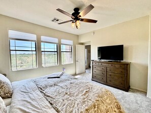 A bedroom with a bed, a dresser, a television, and a ceiling fan. - Vistoso Condo #212C (Oro Valley)
