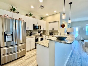 A modern kitchen with stainless steel appliances, a marble countertop, and pendant lighting. - Vistoso Condo #212C (Oro Valley)
