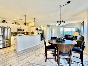 A modern kitchen with stainless steel appliances, a central island, and pendant lighting. - Vistoso Condo #212C (Oro Valley)