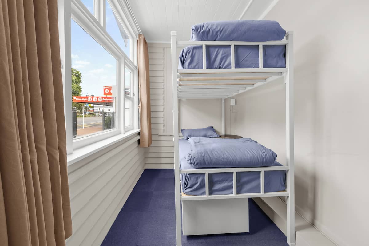 A bunk bed room with a window, curtains, and a view of a red bridge.