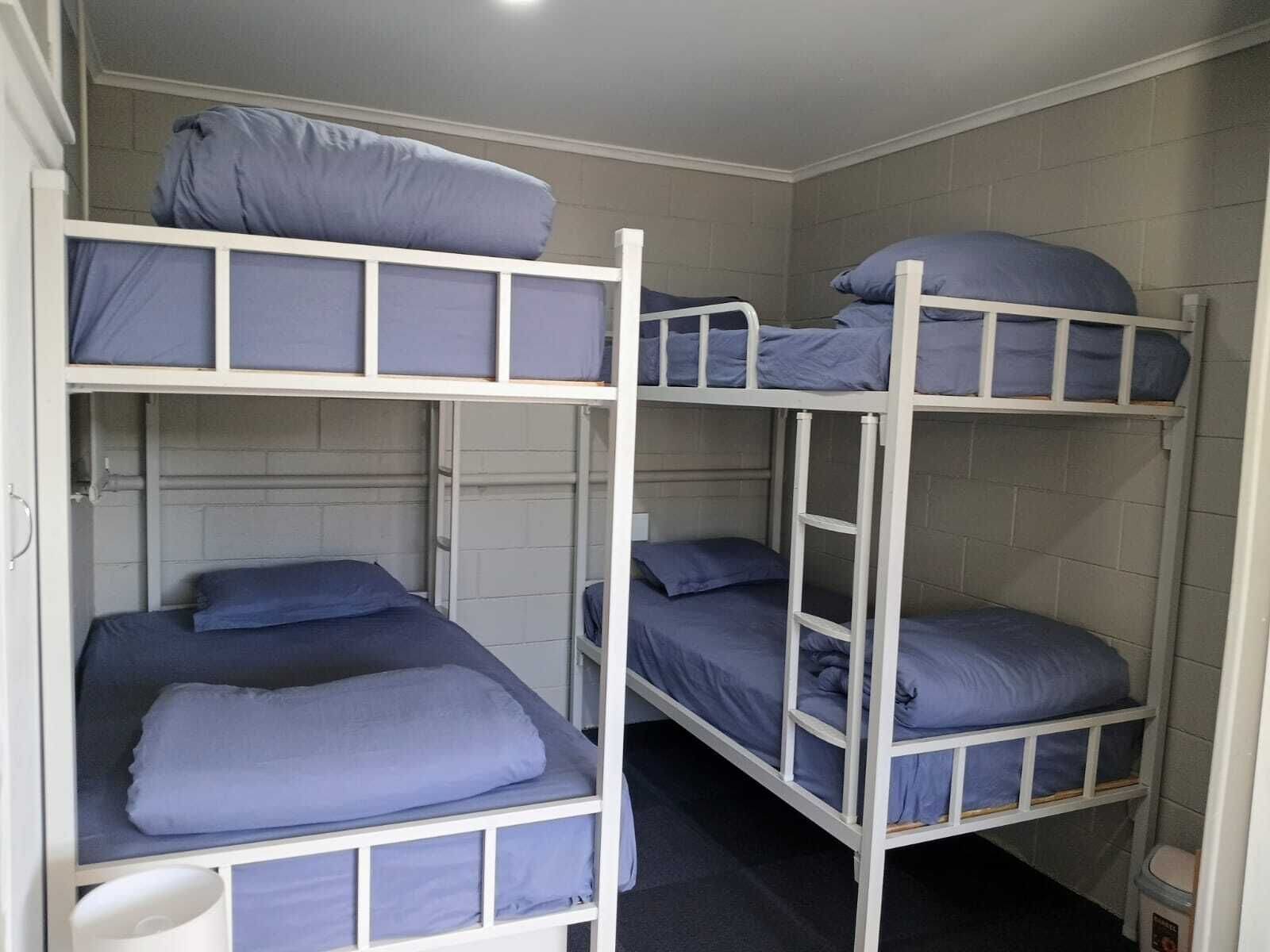 A bunk bed room with white metal frames and blue bedding.