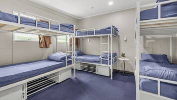 A bunk bed room with a small table and a window.