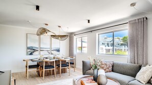 Un salon moderne avec un coin repas, de grandes fenêtres et une vue sur les immeubles.