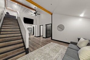 Un intérieur moderne avec un escalier, un espace de vie doté d’un canapé et une cuisine en arrière-plan.
