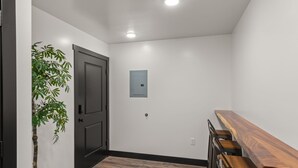 Um corredor com um banco de madeira, uma porta e um interruptor de luz na parede.