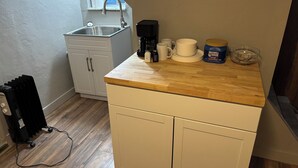 A compact kitchen with a wooden countertop, white cabinets, a sink, and a coffee maker. - Cozy Private Studio w/ Kitchenette (Pittsburgh)