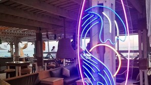 Uma área de estar acolhedora com um letreiro de neon que diz "SOUL" e vista para o mar.