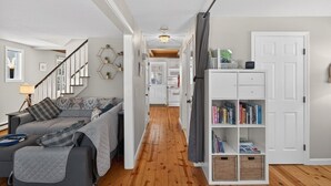 Ein modernes Wohnzimmer mit einem grauen Sofa, Holzboden und einer Bücherwand voller Bücher.