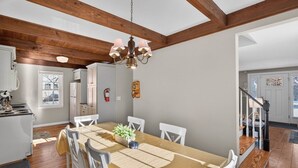 Ein geräumiger Essbereich mit einem langen Holztisch, weißen Stühlen und einer Kandelaber.