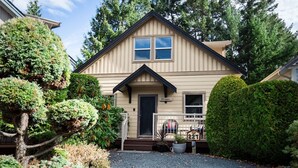 A single-story house with a dark front door, a small porch with a railing, and a mailbox with the number 227. - Cottage at Oceanside Village Resort - Sandpiper (Parksville)