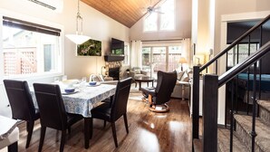 A spacious dining area with a wooden ceiling, a fireplace, and a view of the outside. - Cottage at Oceanside Village Resort - Sandpiper (Parksville)