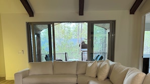 Ein großes, L-förmiges Ecksofa in einem geräumigen Wohnzimmer mit einem großen Schiebeglastür, die auf einen Balkon führt.