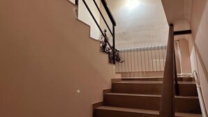 Un escalier avec une rampe, des murs de couleur beige et un luminaire au plafond.