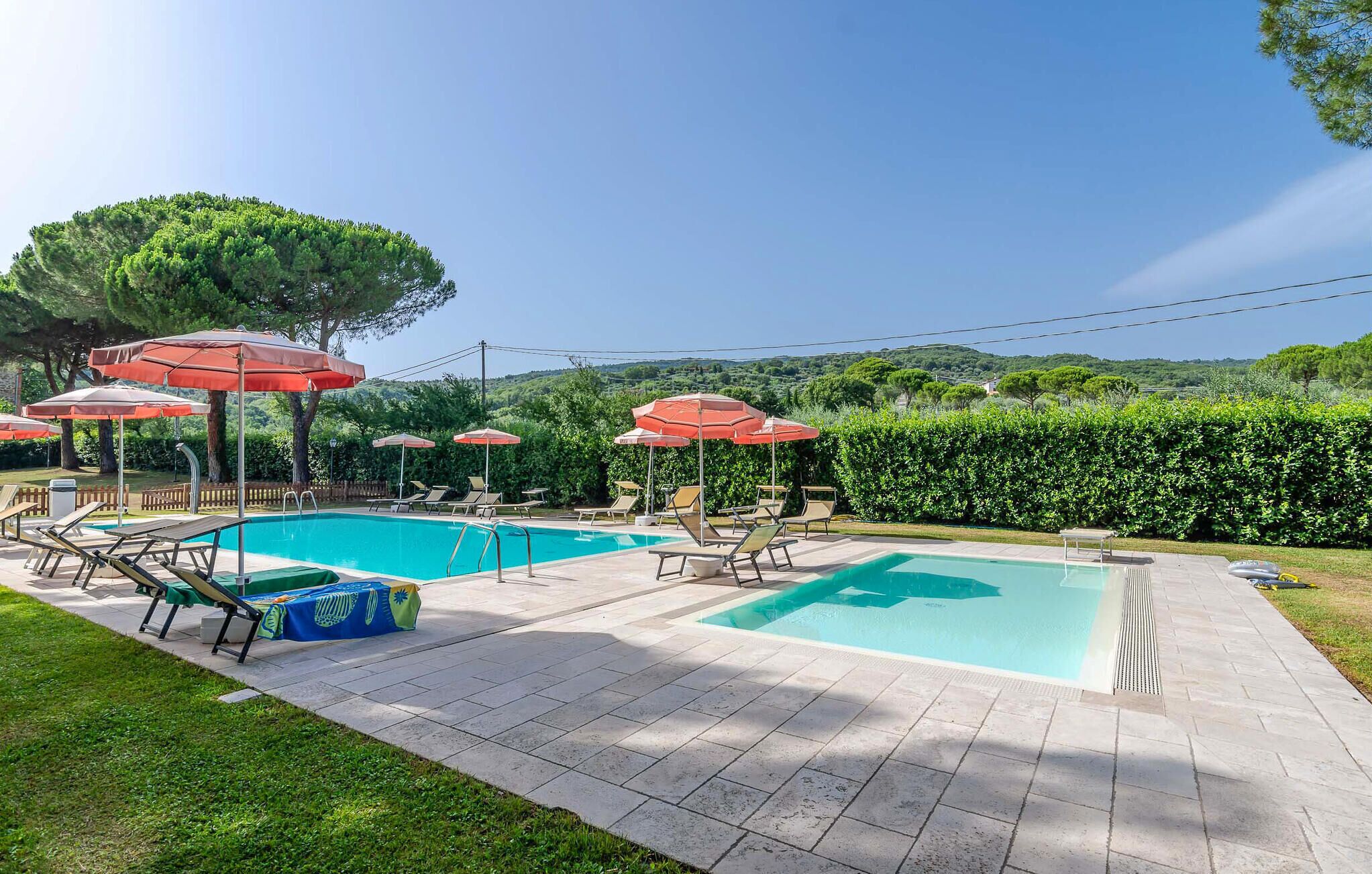 A pool area with two pools, lounge chairs, and umbrellas.