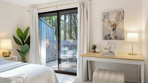 A modern hotel room with a bed, a desk, a chair, a plant, and a painting. - Marbella Lane-Cozy Luxury Townhome near Microsoft (Bellevue)