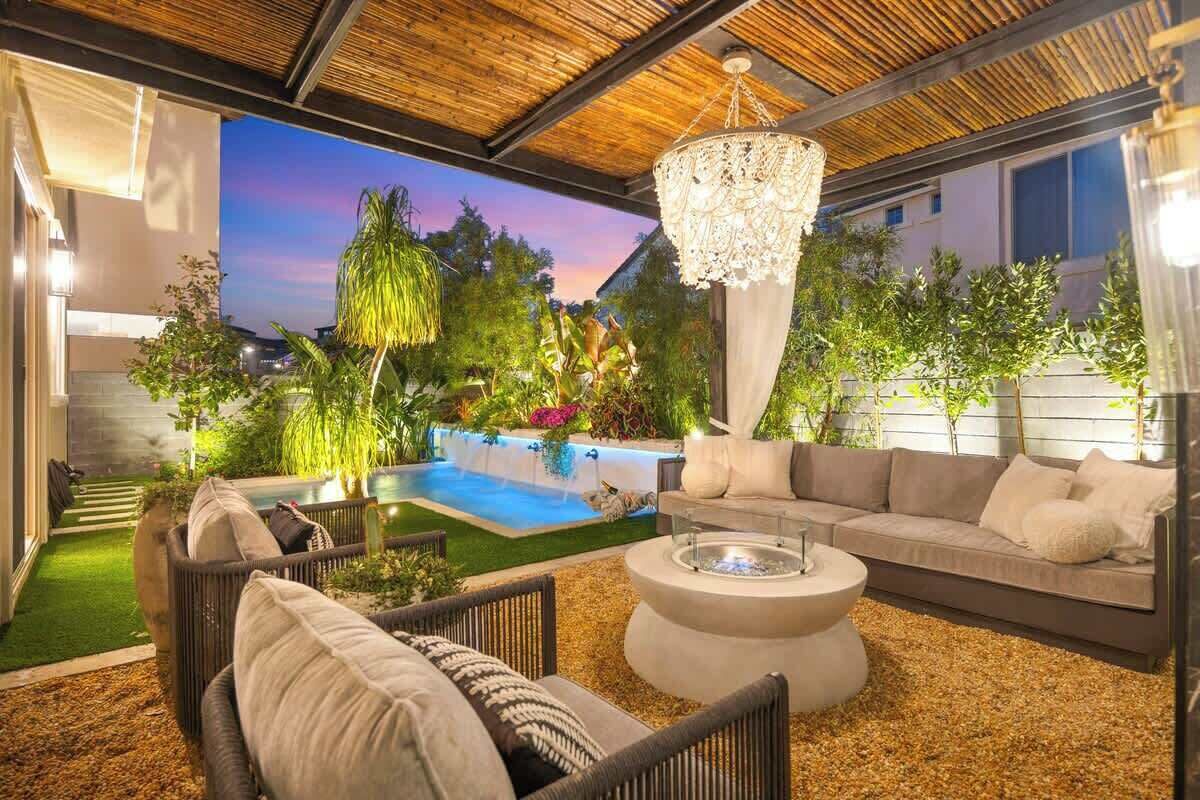 Un espace de vie extérieur moderne comprenant une piscine, un canapé et un foyer.