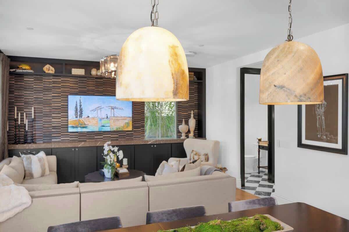 A modern living room with a sectional sofa, a dining table, and two pendant lights.