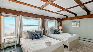 A room with two beds, a desk, and a window with curtains.