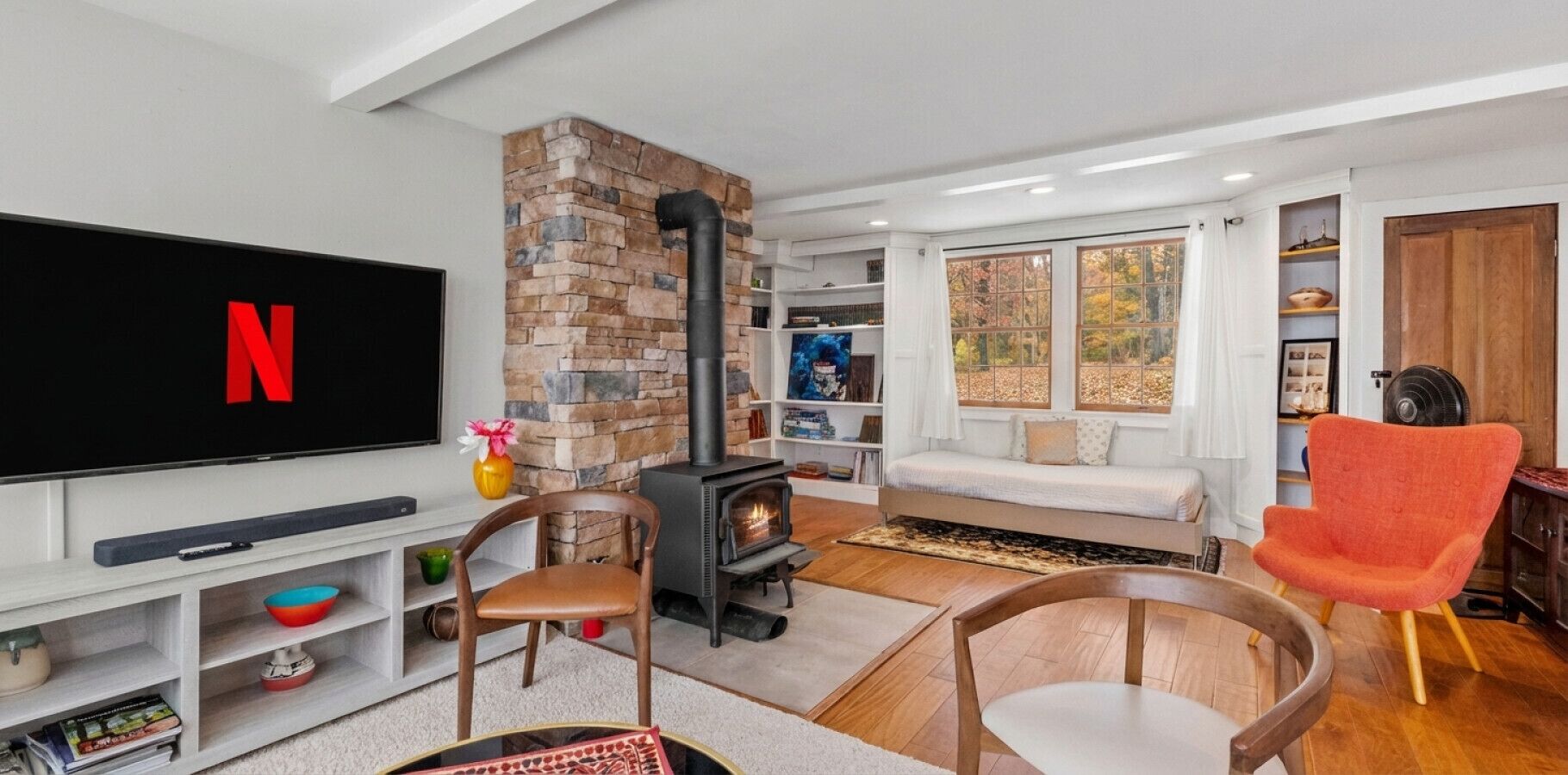 A living room with a TV, a fireplace, a sofa, and a red chair.