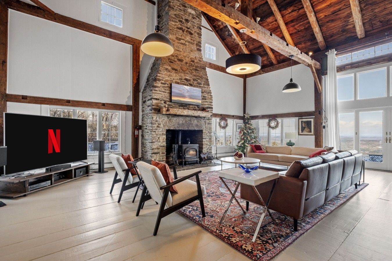 A spacious living room with a stone fireplace, a large flat-screen TV, and a cozy seating area.