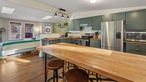 A modern kitchen with a central island, stainless steel appliances, and green cabinets. - Bear Den: Hot Tub + Secluded | Sleeps 8 | Modern (Wardsboro)