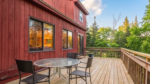 Ein rotes Holzgebäude mit einer Terrasse, einem Glastisch und Stühlen.