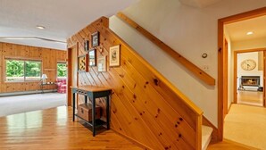 Ein Holzinnenraum mit Treppe, Kamin und gerahmten Bildern an der Wand.