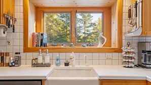 Eine Küche mit Fenster, Holzschränken, einer Spüle und einer Kaffeemaschine.