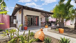 A modern house with a patio, surrounded by cacti and a palm tree. - Boat House with air conditioning in the living room and communal pool (Kralendijk)