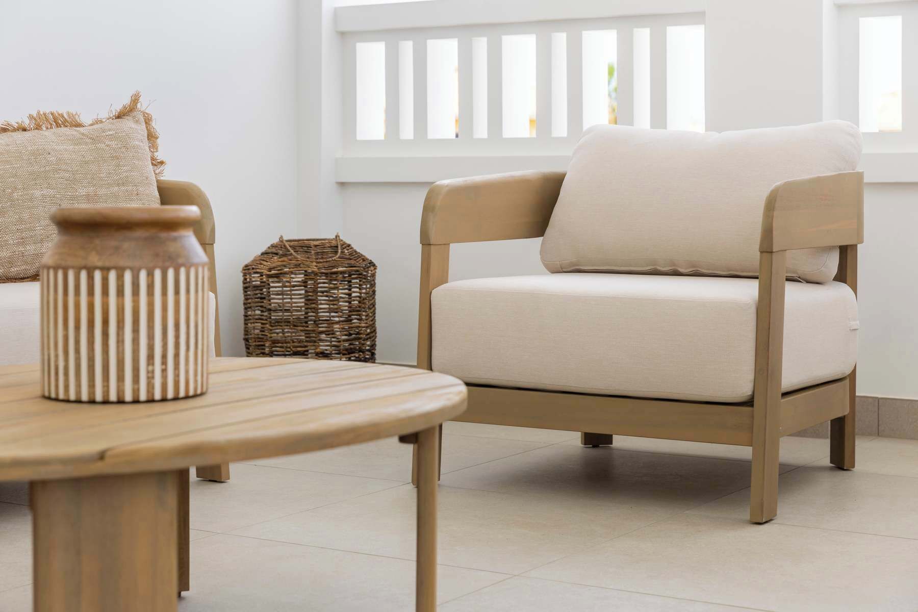 Un salón minimalista con un sofá color beige, una mesa de madera y una cesta de mimbre.