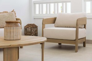 Ein schlichter Raum mit einem hellen Sofa, einem Holztisch und einem Korbwäschesammler.