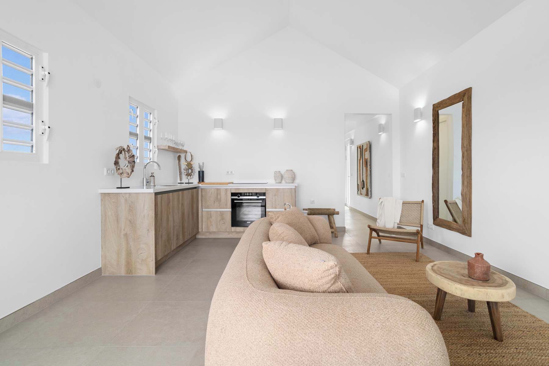 Ein modernes Wohnzimmer mit einem beigefarbenen Sofa, einem Holztisch und einem großen Spiegel an der Wand.