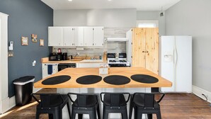 Une cuisine moderne dotée d’un îlot central, de meubles blancs, d’un mur d’accent en bois et d’un réfrigérateur blanc.